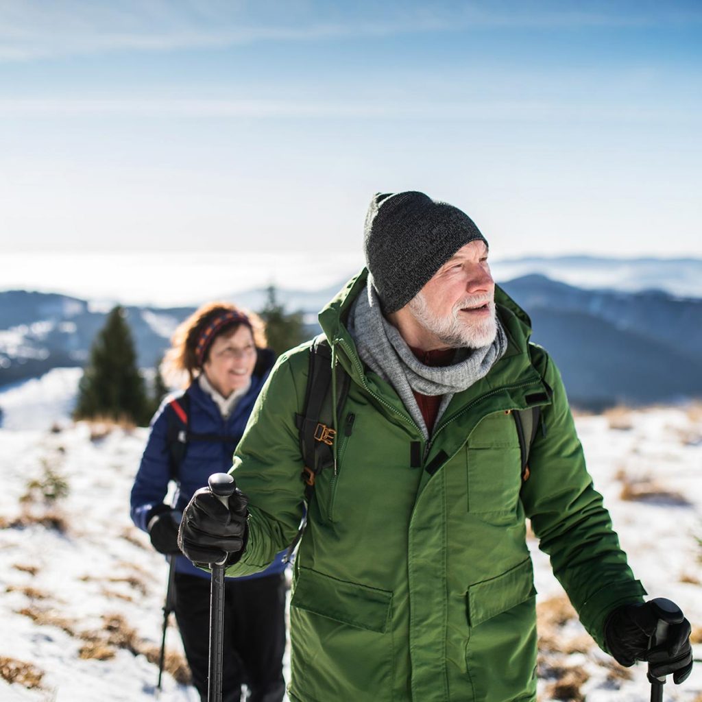 retired couple hiking in snowy mountains